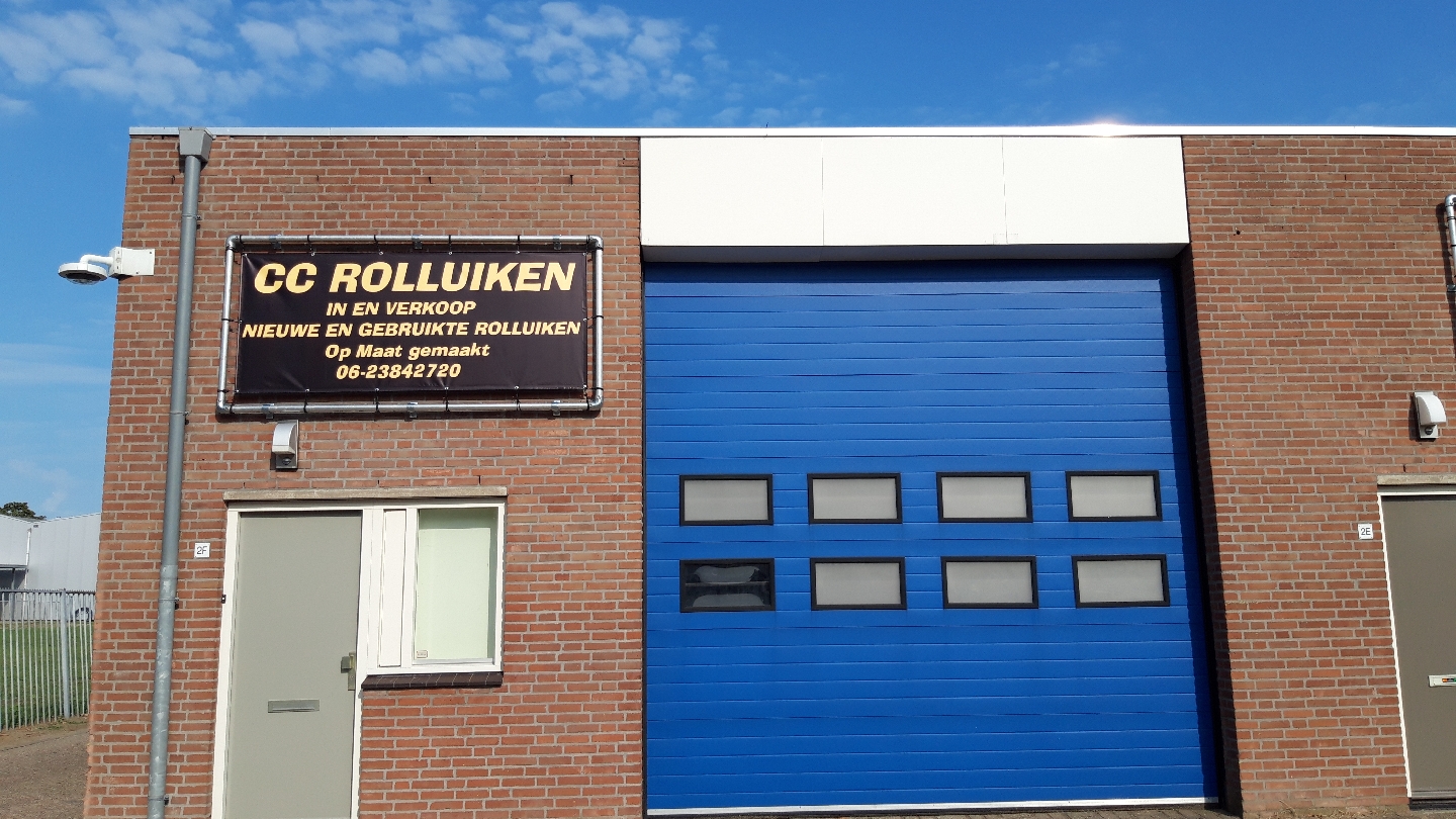 De showroom van Cc rolluiken aan de Sluisweg in Waalwijk: bruin spandoek met gouden letters naast een blauwe sectionaaldeur