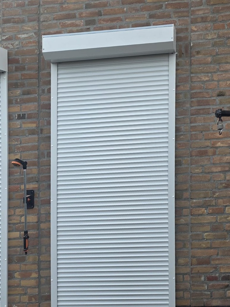 Vers gemonteerd wit rolluik met kast op een bakstenen achtergevel